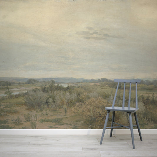 Eowyn Wallpaper with a gray chair in front of a scenic wall mural with a landscape.