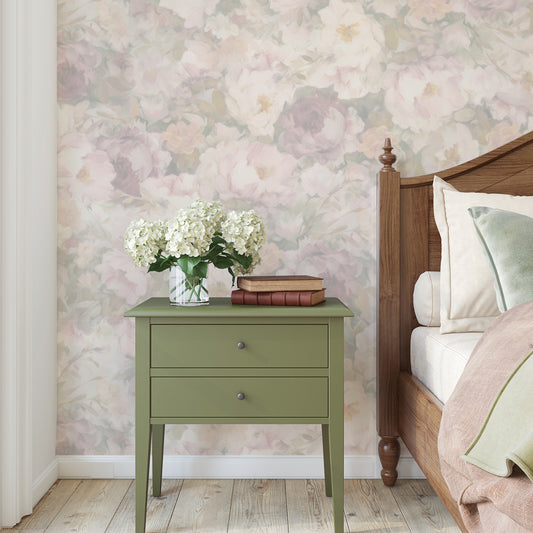 Green nightstand with flowers and books against a floral wallpapered wall.