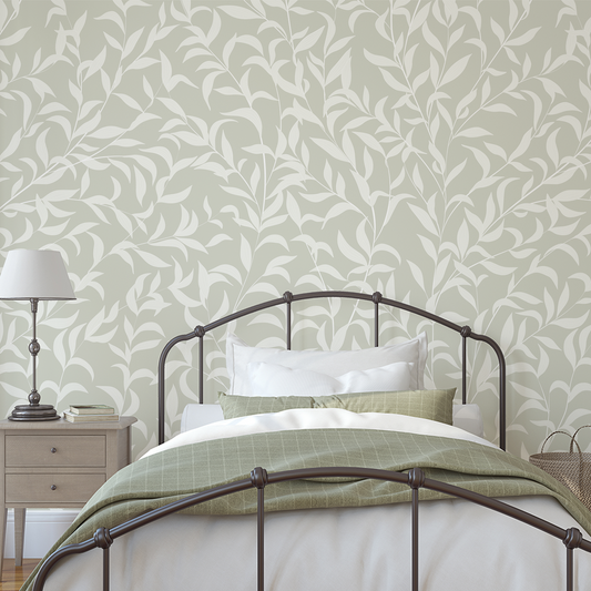 Bedroom with a bed against a wall featuring a leaf patterned wallpaper.