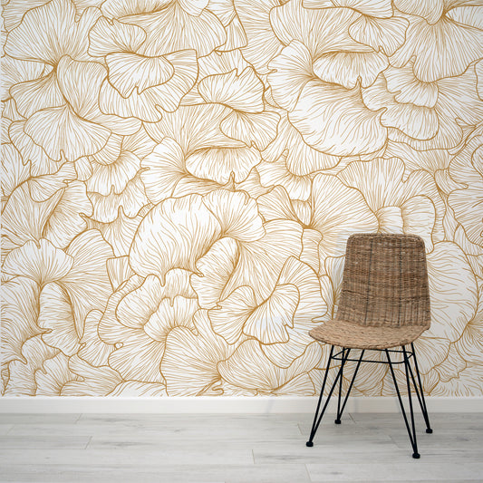 Chanterelle Gold Wallpaper with a Wicker chair against a wall with floral patterned wallpaper