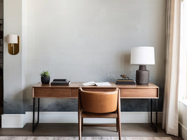 Modern home office with wooden desk, chair, and decor elements.