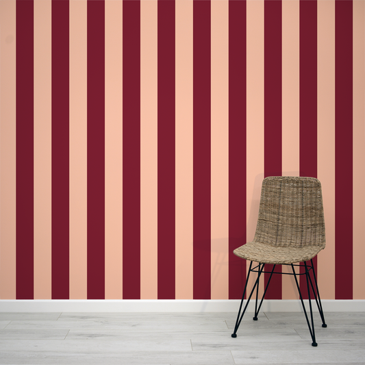 Dark red and light pink striped wallpaper with a wicker chair 
