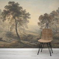 Wicker chair in front of a wall mural depicting a misty landscape with trees and animals.