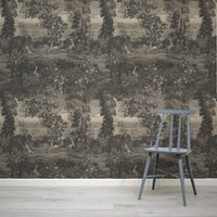 Katharine Mono Wallpaper with nature-themed design featuring trees and animals, paired with a wooden chair.