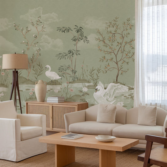 A styled living room featuring a sage green wall with a delicate botanical and swan mural, decorated with a beige sofa, wooden coffee table, and a floor lamp.