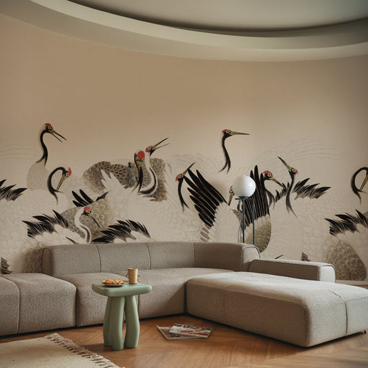 A modern living room setup featuring a large beige sectional sofa with a matching ottoman, a small mint green side table, and a wall mural decorated with black and gray cranes on a beige background.