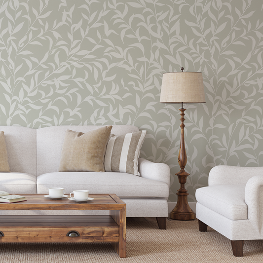Living room with white sofa, wooden coffee table, and lamp against a leaf-patterned wall.