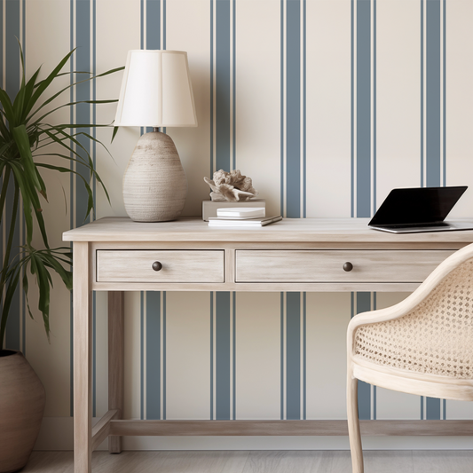 Home office setup with a desk, lamp, and chair against striped wallpaper.