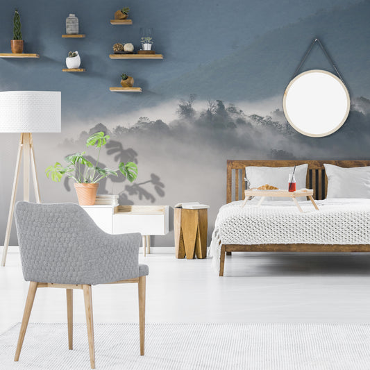Mystical Morning Haze wallpaper in bedroom with wooden bed and white bedding with breakfast on bed including cranberry juice in a glass and a croissant on a plate as well as a large green plant on a side table with other small plants on the wall