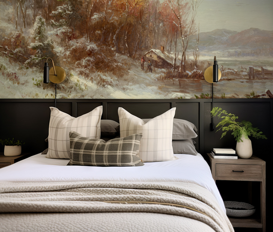 Bedroom with a large winter landscape painting on the wall, featuring a bed with plaid pillows and nightstands.