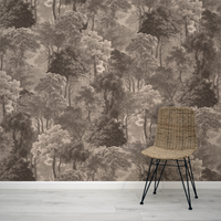 Wicker chair in front of a forest wallpaper design on a wall.