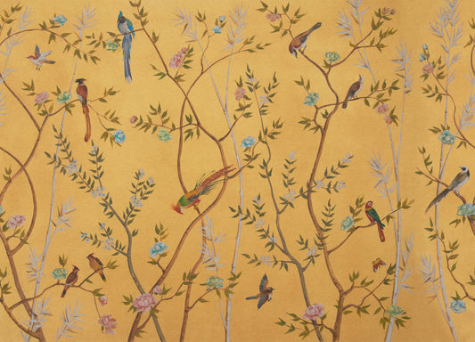 A close-up of a decorative wallpaper or fabric pattern featuring a warm mustard yellow background with delicate branching vines, small leaves, pink and blue flowers, and numerous birds in blue, green, brown, and red tones.